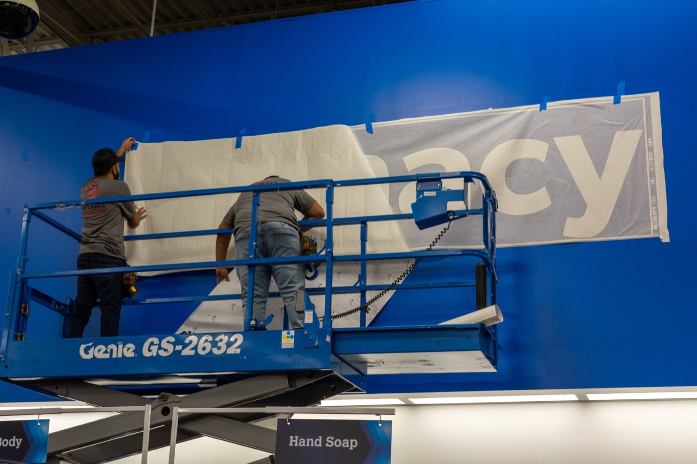 Installers on a lift applying a large wall graphic